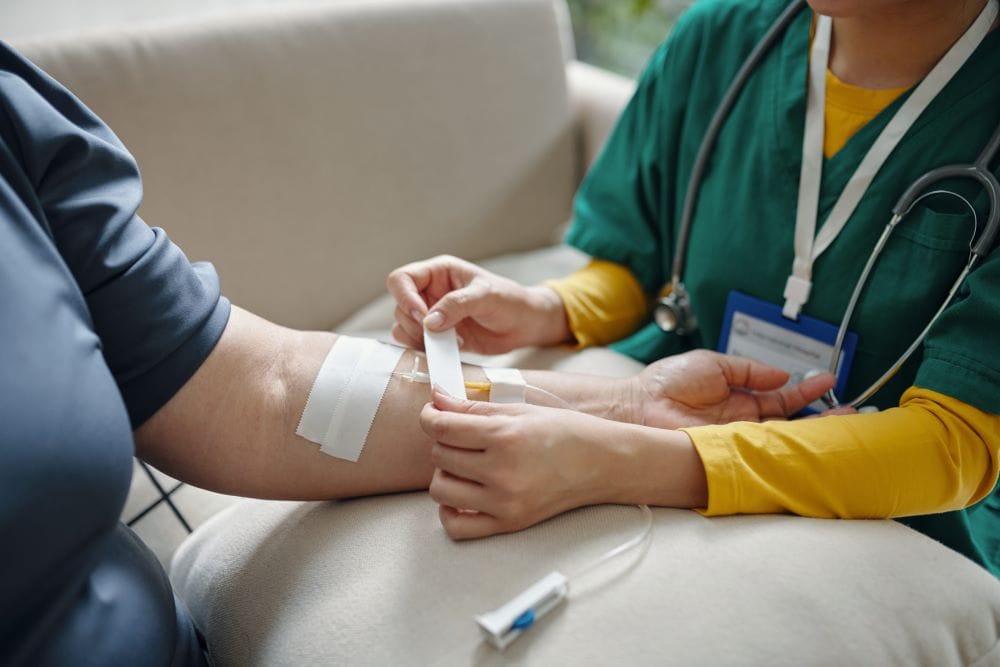 A clinician administering an IV drip to a patient as part of her IV therapy package.